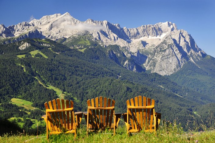 Drei Holzstühle vor Berglandschaft