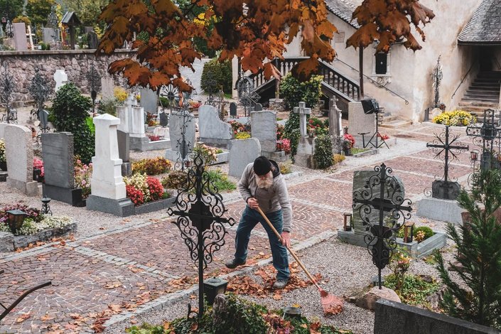 Der Friedhofswärter beim Zusammenrechen vom Laub