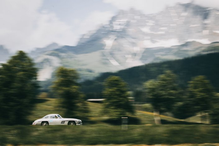 Ein weißes Oldtimer Rennauto vor der Bergkulisse des Wilden Kaisers im Sommer