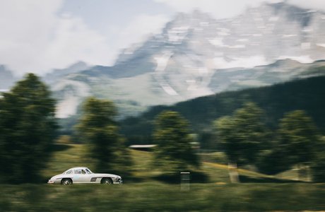 Ein weißes Auto vor der Kulisse der Berglandschaft des Wilden Kaisers