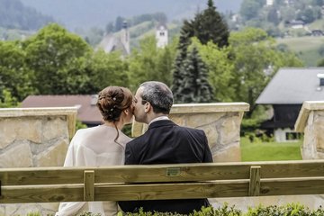 Hochzeitspaar auf Bank von hinten