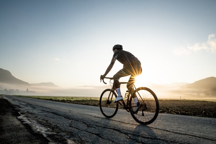 Mann fährt mit dem Rennrad zum Sonnenaufgang