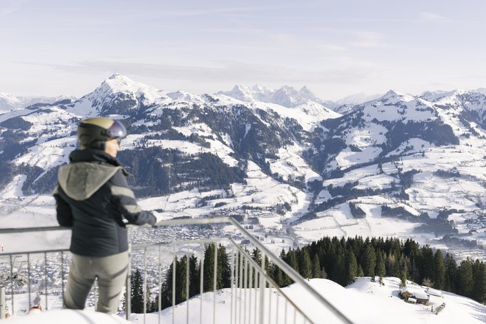 Frau genießt beim Skifahren den Ausblick über Kitzbühel