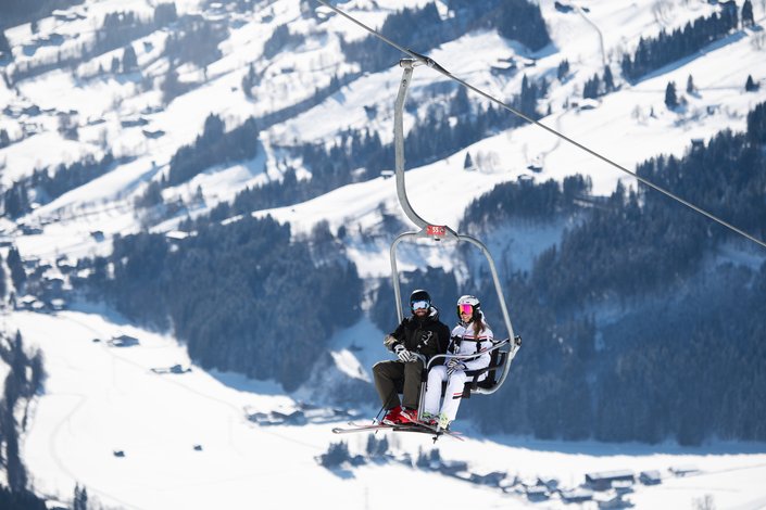 Paar fährt mit einem 2er Sessellift zum Skifahren auf die Bichlalm