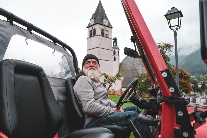 Der Friedhofswärter in seinem roten Jeep von der Seite